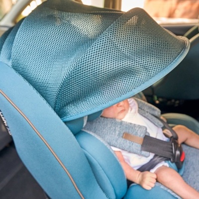 Cadeira auto azul com bebé e cobertura de rede no banco traseiro do carro
