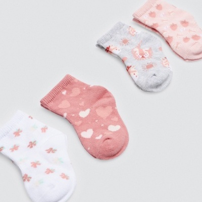 Quatro meias de bebê coloridas com padrões sobre fundo cinza claro