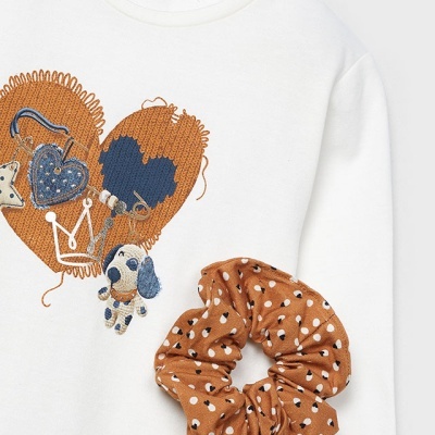 Camisola branca com coração bordado e elástico de cabelo castanho com manchas pretas e brancas