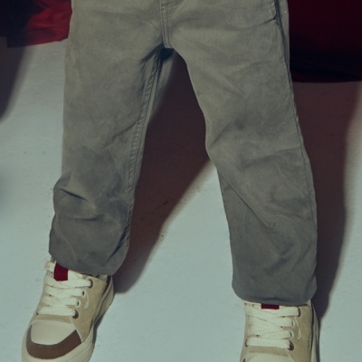 Calças cinza de algodão e ténis brancos com detalhes castanhos e vermelhos em criança