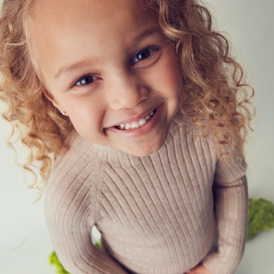 Camisola infantil bege de malha com nervuras em criança sorridente