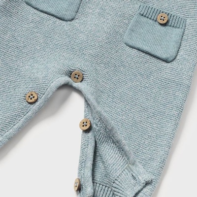 Macacão de malha azul claro com botões de madeira e bolsos pequenos