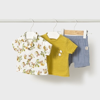 Três peças de roupa infantil penduradas, incluindo camisa com padrão de abelhas, t-shirt amarela e calções cinzentos azuis.