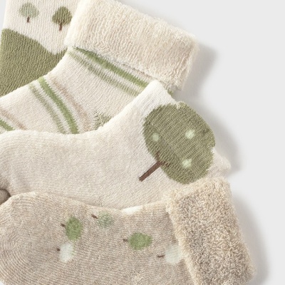 Três meias de bebé em tons de bege, branco e verde com padrões de árvores e riscas.