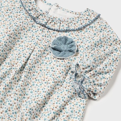 Camisola de bebé branca com pintas azuis e castanhas, gola e detalhes decorativos azuis.