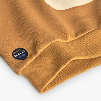 Roupa amarelo mostarda com etiqueta redonda azul 'discover boboli world'