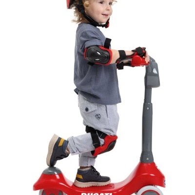 Criança de capacete vermelho em trotinetes vermelha Ducati