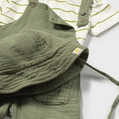 Conjunto de roupa de bebê com t-shirt às riscas, salopete verde e chapéu verde.