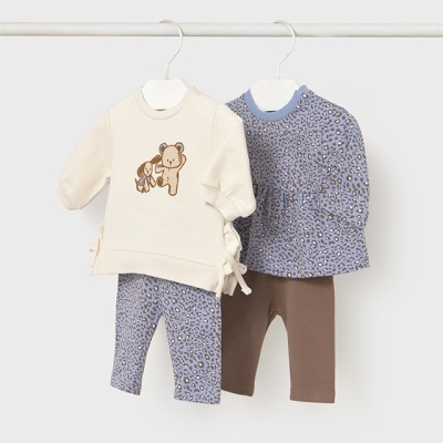 Dois conjuntos de roupa de bebé pendurados em cabides brancos, um creme com estampado de ursos e outro azul com padrão de manchas.
