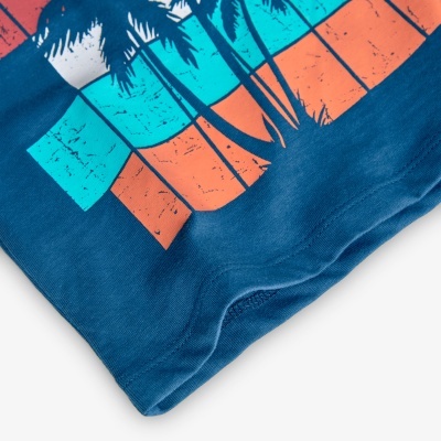Detalhe da parte inferior de uma t-shirt azul com padrão colorido e palmeiras pretas