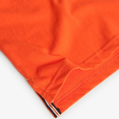 Bainha de peça de roupa laranja com faixa colorida na costura