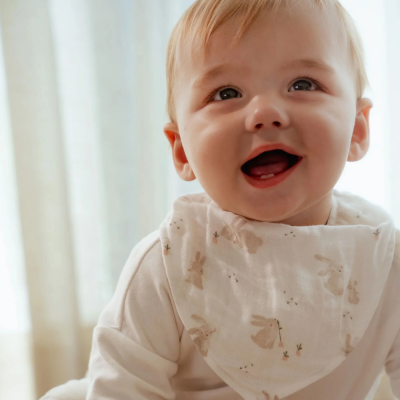 Bebé sorridente com babete branco estampado de coelhinhos