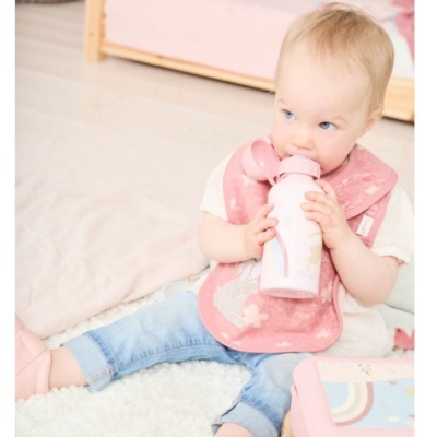 Bebé com biberão rosa e babete cor de rosa sentado no chão
