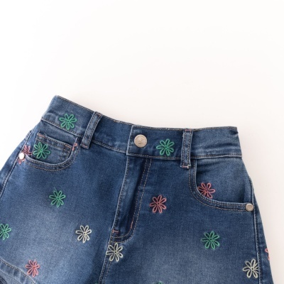 Calções de ganga azul com bordados florais coloridos e botão metálico.