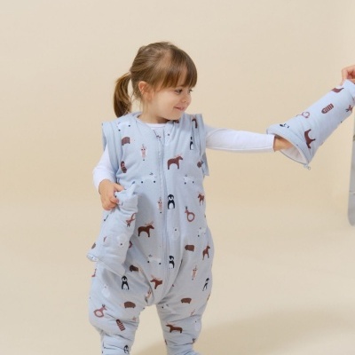 Criança com macacão azul claro estampado de animais e manga removível