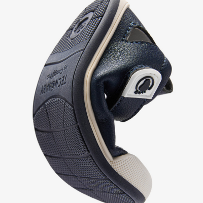 Sapatilha flexível azul escuro para bebé com sola preta e branca e etiqueta com símbolo de pé