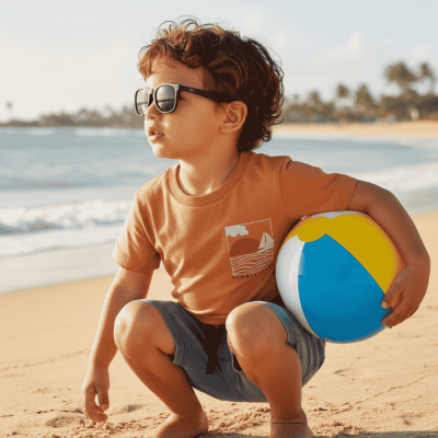 Criança com óculos de sol na praia segurando bola de praia colorida