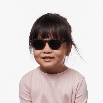 Criança com óculos de sol castanho-escuros e camisola rosa