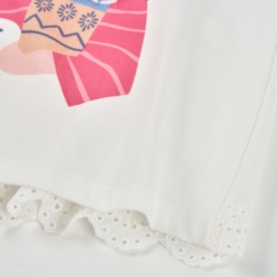 Detalhe de roupa branca com estampado colorido e renda na bainha.