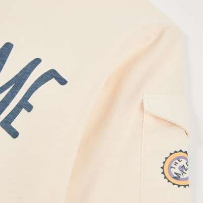 T-shirt creme com estampado azul e bolso na manga com logo THE MAZAR