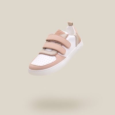 Ténis bege e branco com velcro e sola branca sobre fundo bege claro