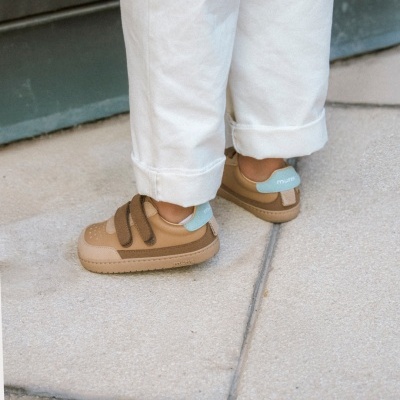 Sapatos infantis castanhos com velcro em chão de pedra claro