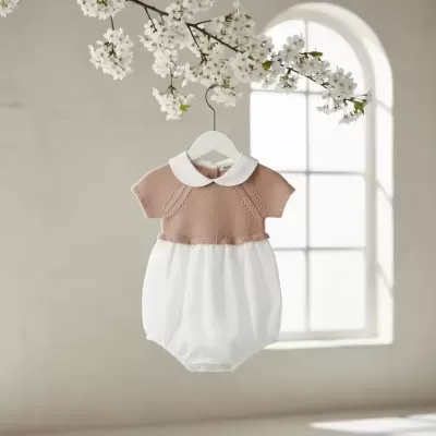 Macacão de bebé cor de rosa e branco pendurado com flores brancas no topo