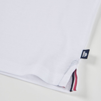 Detalhe da parte inferior de peça de roupa branca com etiqueta azul e fita colorida