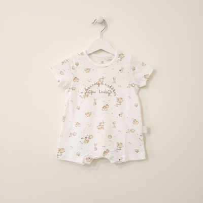 Macacão curto branco para bebé com padrões de ovelhas e coelhos e texto frontal, pendurado em cabide branca.