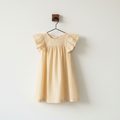 Vestido infantil amarelo com riscas brancas pendurado num cabide