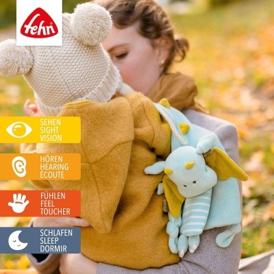 Criança com chapéu de malha e peluche azul com adulto em fundo de parque