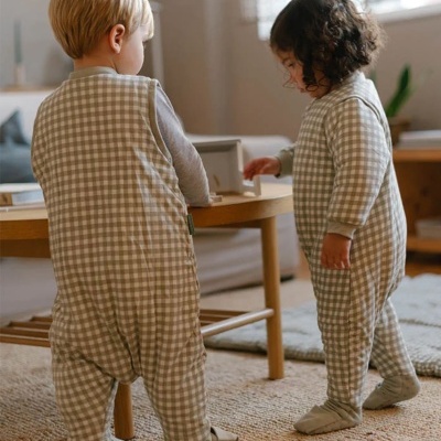 Dois bebés com pijamas xadrez bege e branco em sala de estar