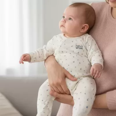 bebé com macacão bege claro com flores azuis e texto make a WISH