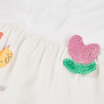 Vestido branco com bordado de flor rosa em croché e estampado colorido