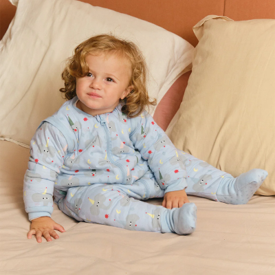 Bebé sentado em macacão azul claro com elefantes e estrelas