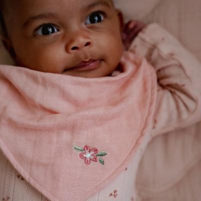 Babete triangular cor-de-rosa com bordado de flor usado por bebé
