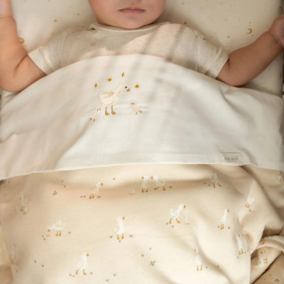 Cobertor de bebé beige e branco com padrão de patos e estrelas, etiqueta little dutch.