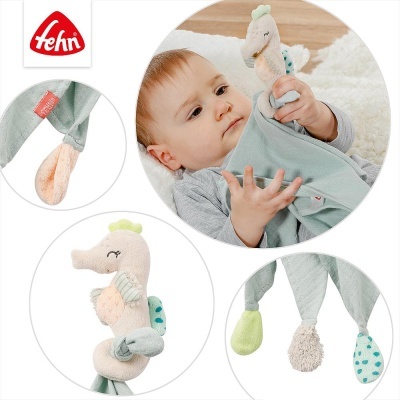 Brinquedo de bebé em forma de cavalo-marinho em tecido com várias texturas e pano azul claro.