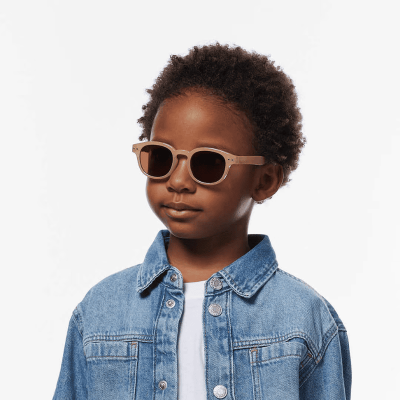 Criança com óculos de sol bege e casaco de ganga azul claro