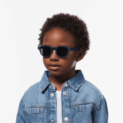 Menino com óculos de sol azuis e camisa de ganga