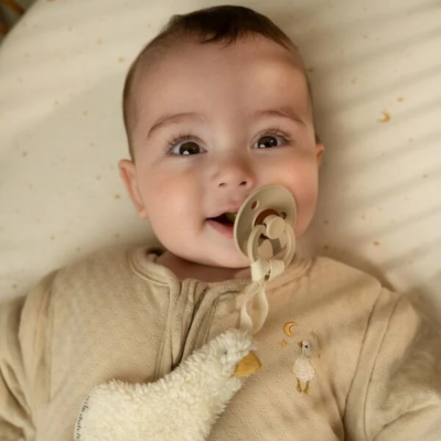 Bebé com chupeta castanha e pijama bege com bordado de ovelha