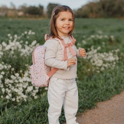 Criança com mochila rosa clara com padrão de flores ao ar livre