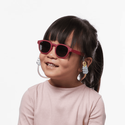 Criança com óculos de sol vermelhos e brincos azuis pendentes