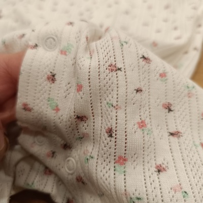 Roupa de bebé branca com padrão floral e fechos de pressão