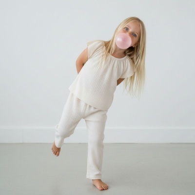 Menina loira com roupa creme a soprar bexiga cor-de-rosa