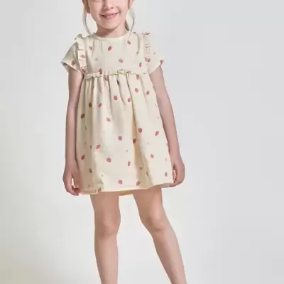 Menina com vestido creme estampado e sandálias castanhas