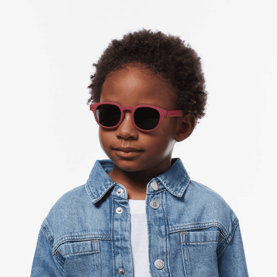 Criança com óculos de sol rosa e casaco de ganga azul