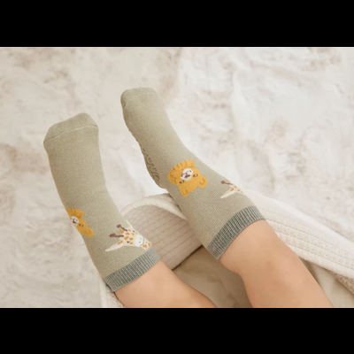 Meias cinza claro com padrão de urso amarelo usadas por pessoa sentada em cadeira branca