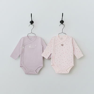 Dois bodys de bebé com mangas compridas, um lilás sólido e outro rosa claro com padrão floral.