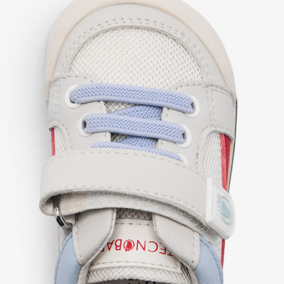 Sapatilha desportiva branca para criança com detalhes azuis e fecho de velcro.